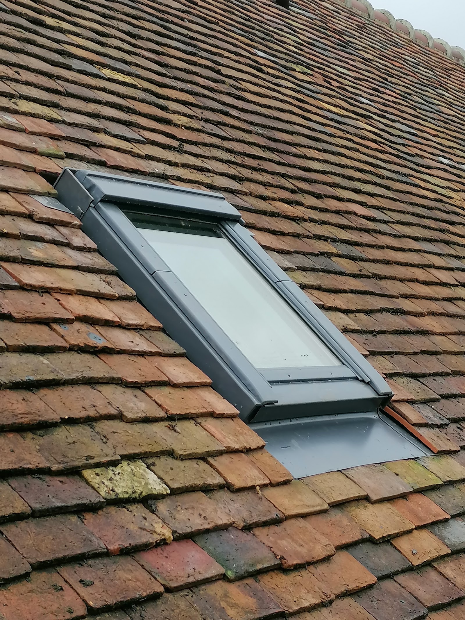 Pose d'une fenêtre de toit Velux sur une couverture en tuiles